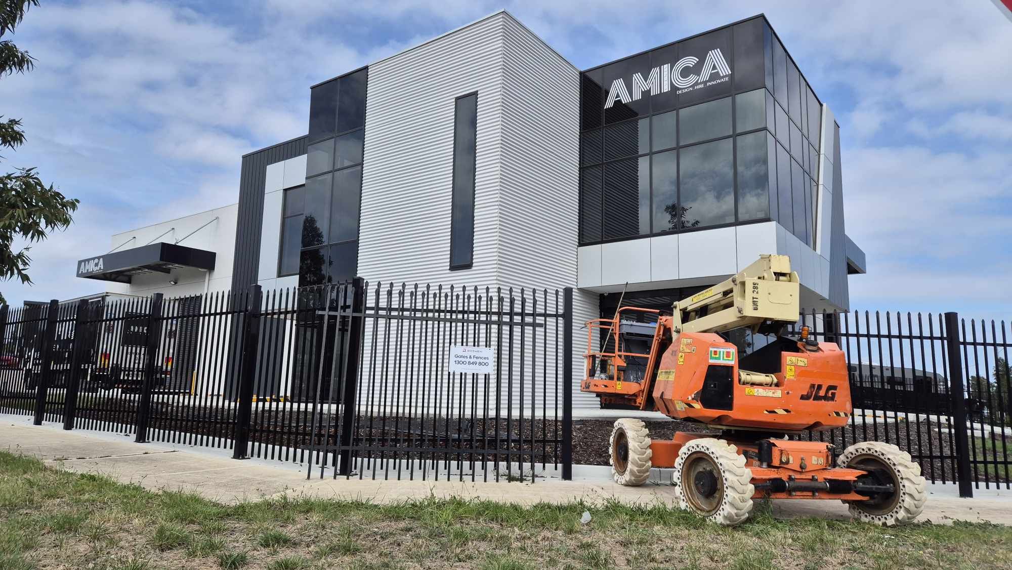 Orange construction lift in front of a building with 'AMICA' branding.