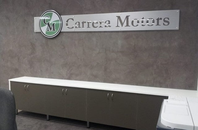 Carrera Motors logo on a wall above a counter using frosted background and round shape over top.