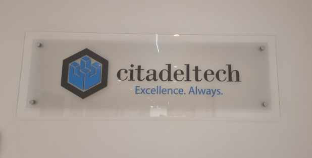 Glass sign with Citadeltech logo and tagline on a white wall