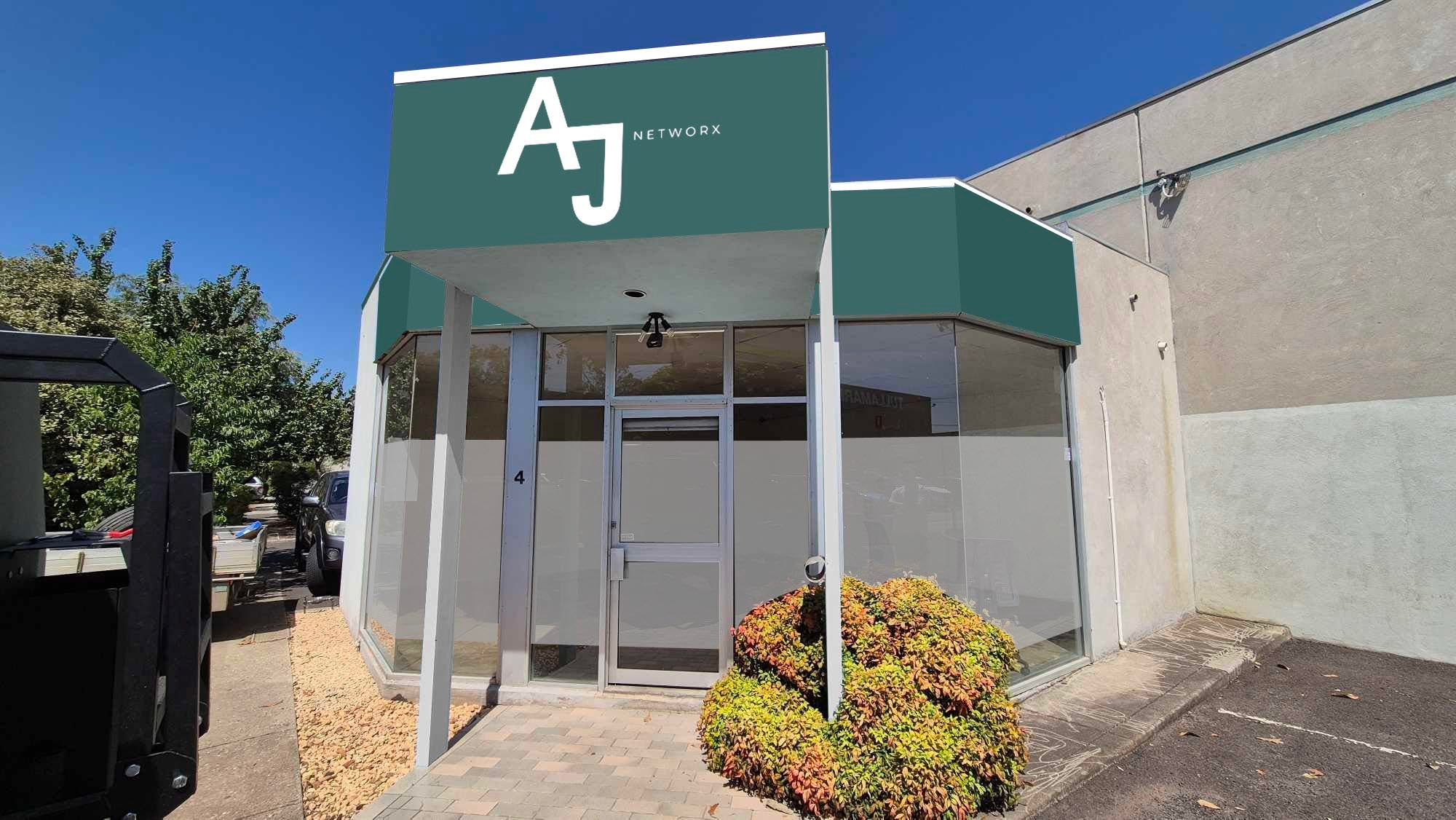Building entrance with 'AJ Network' sign on a clear day