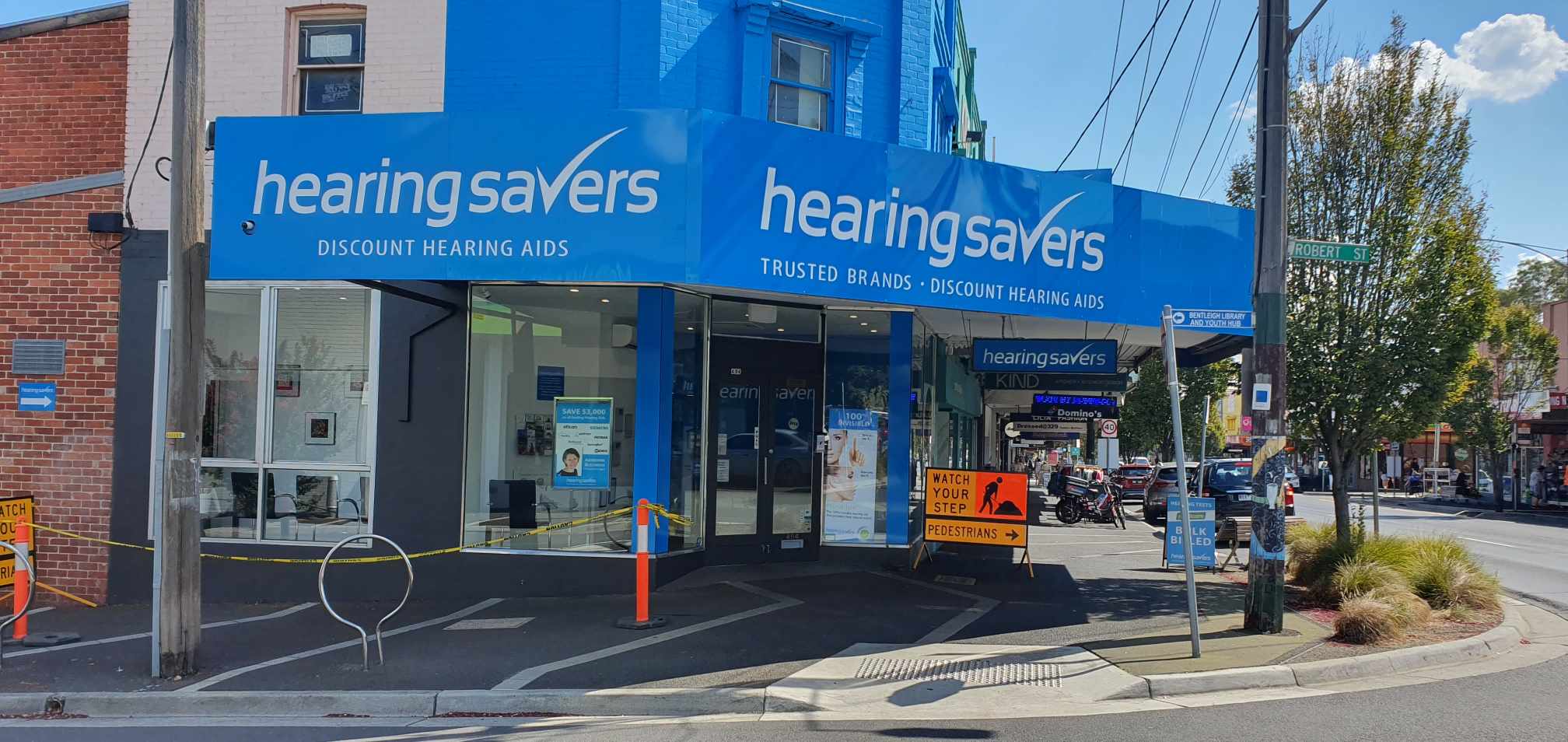 Hearing Savers store front on a city street with clear sky