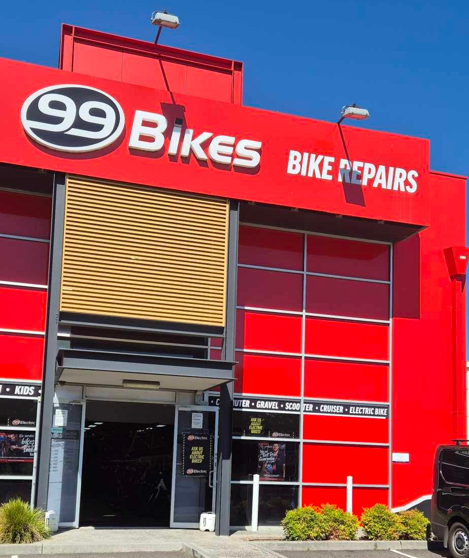 Red building with '99 Bikes' branding and bike repair services on a clear day.