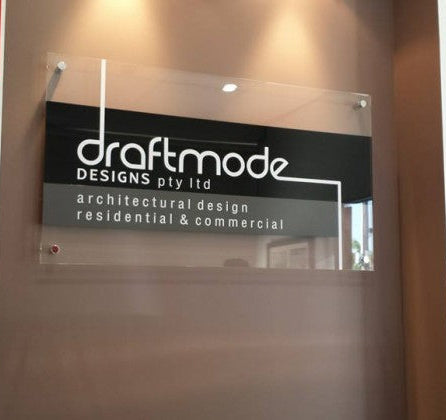 Glass door with 'draftmode DESIGNS pty ltd' sign and two plaques on a wall.
