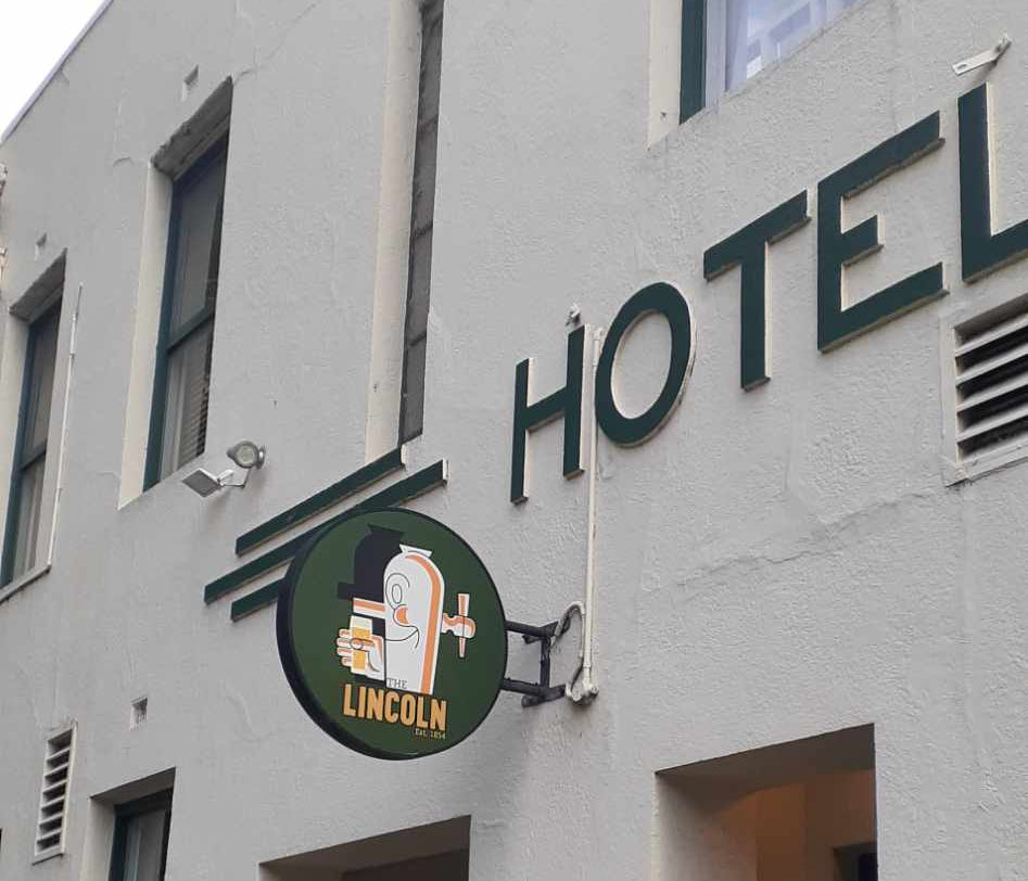 Hotel building with 'Lincoln Hotel' sign on a white and beige facade.