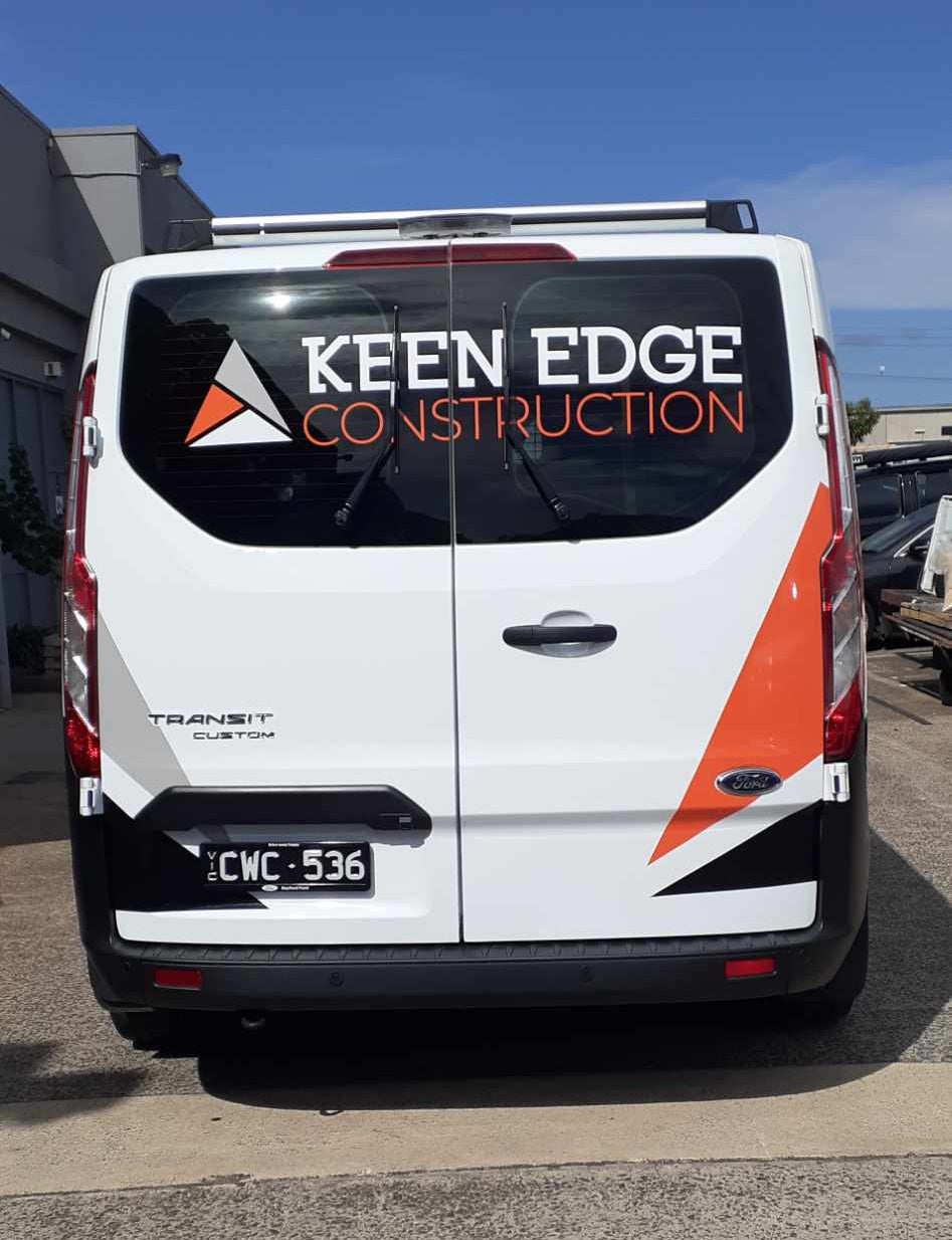 Van with 'Keen Edge Construction' branding on a road.