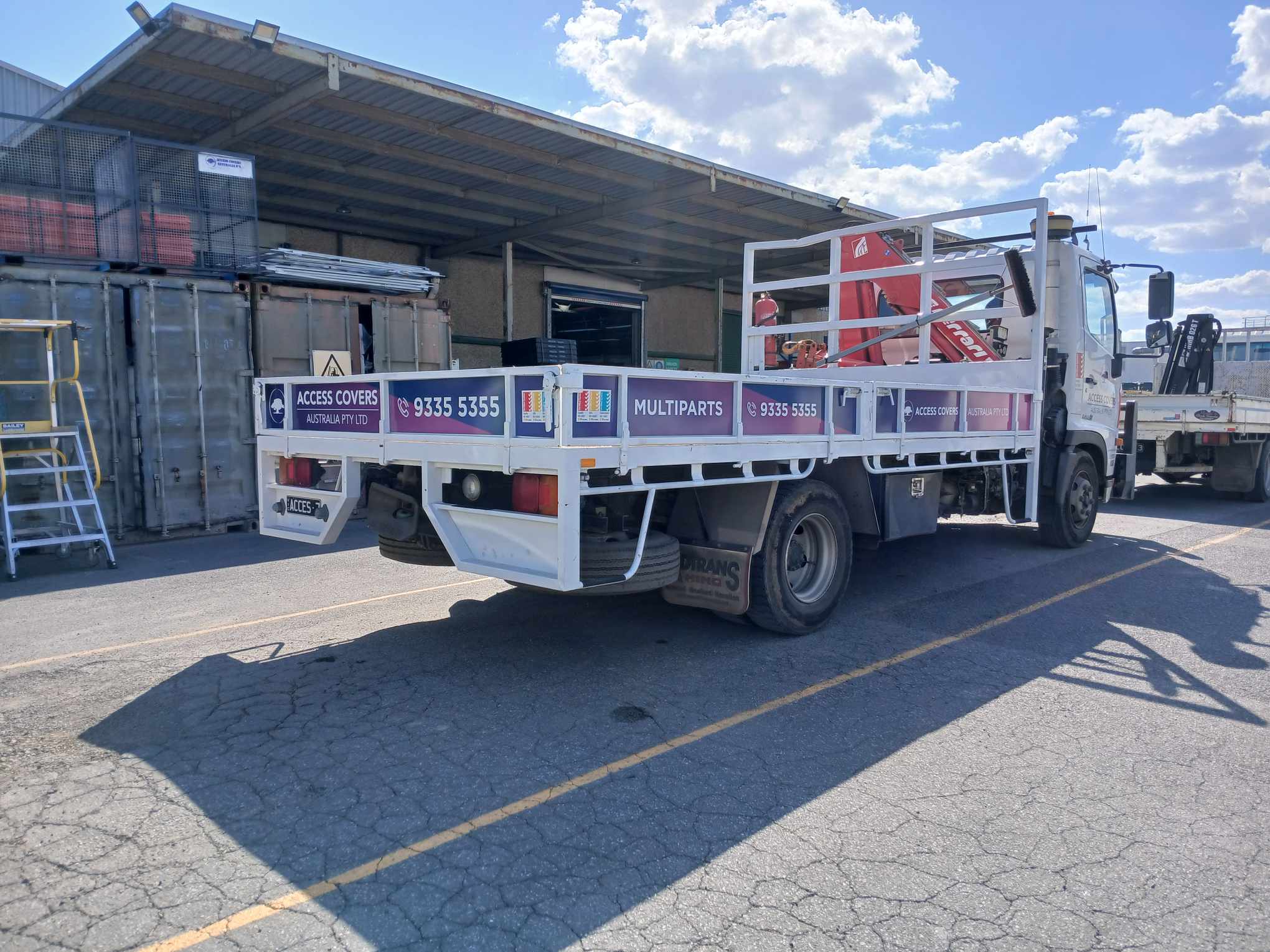 White truck with advertising on a concrete surface under a blue sky.