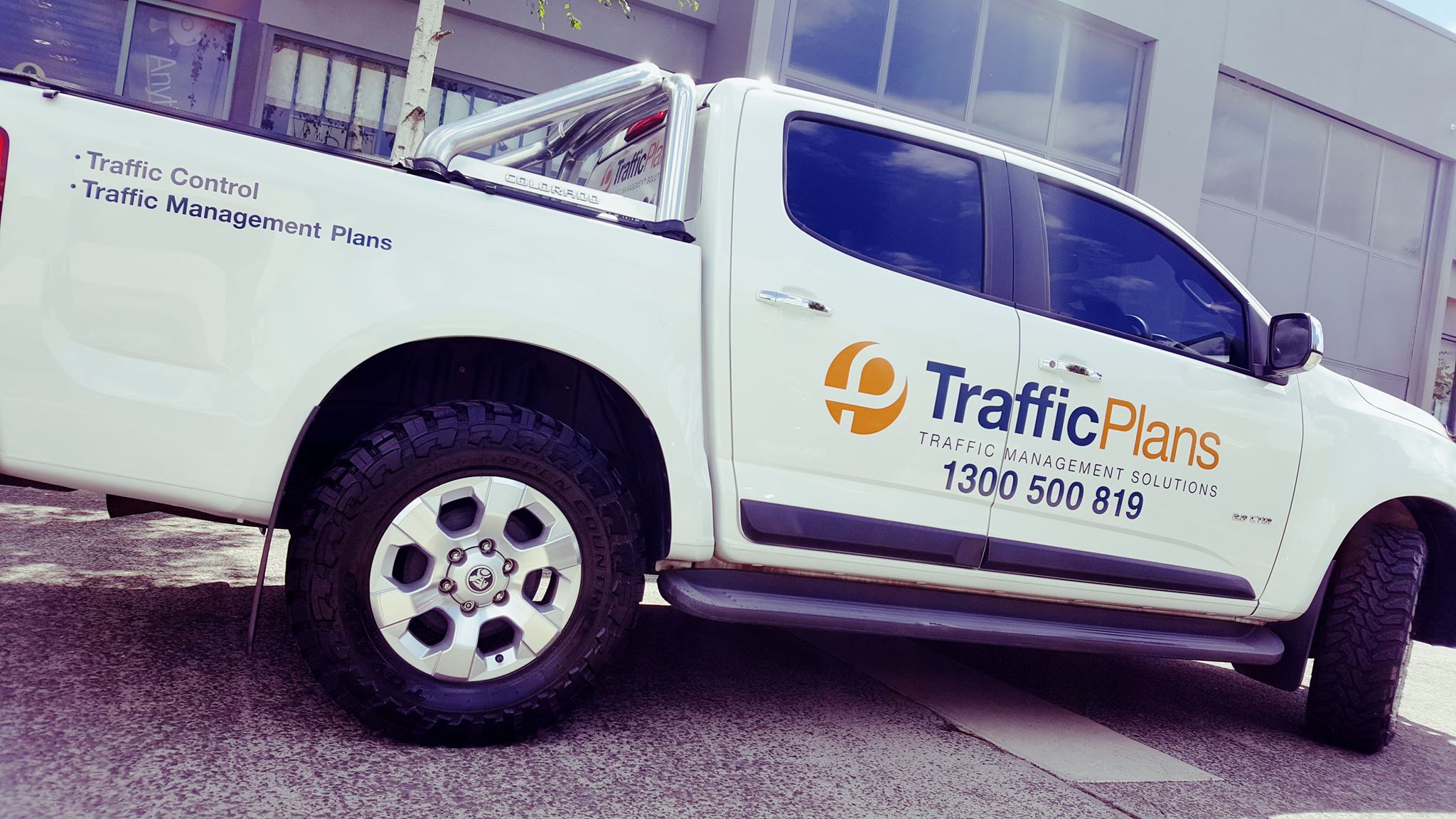 White truck with 'Traffic Plans' branding and contact information on a street. Helps get your contact details to the public. 