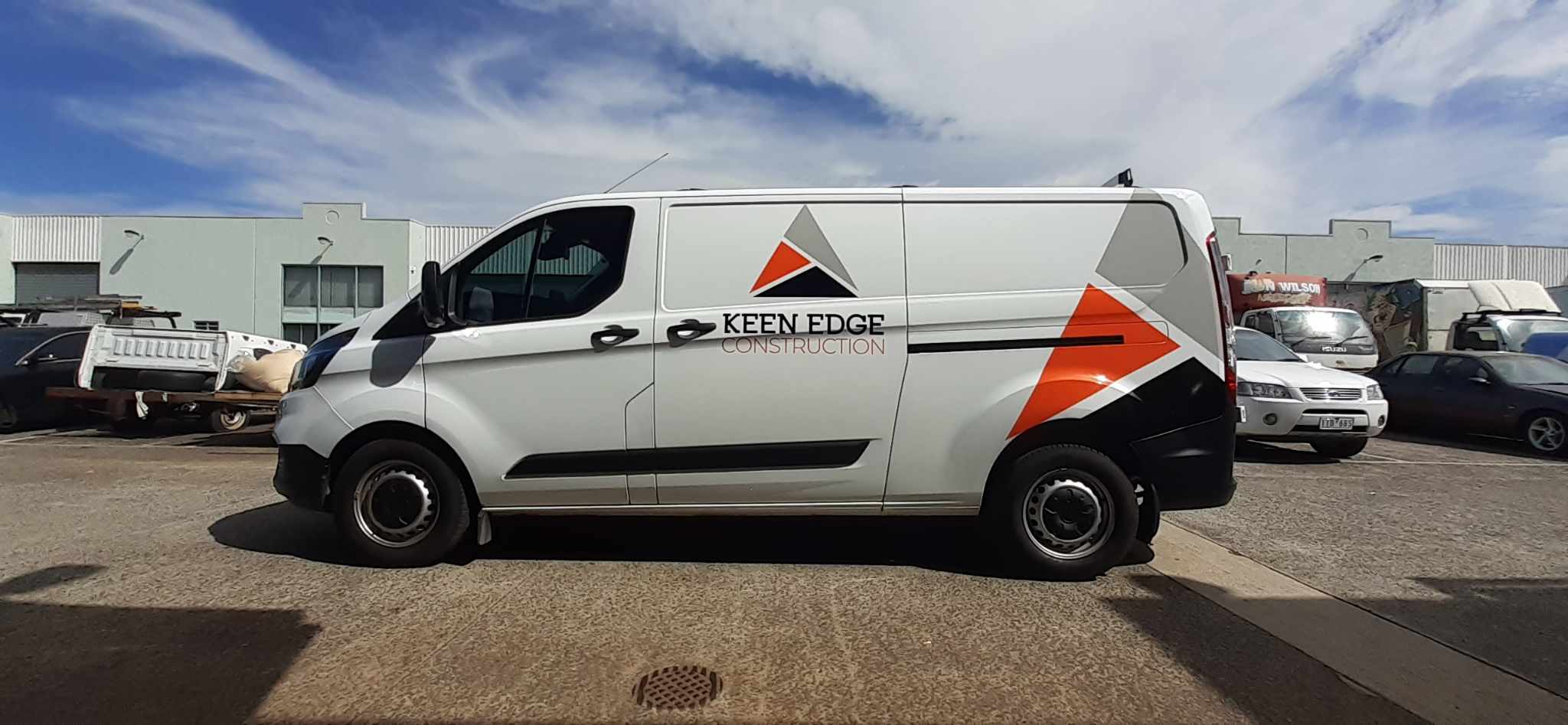 White van with orange and black logo on a parking lot